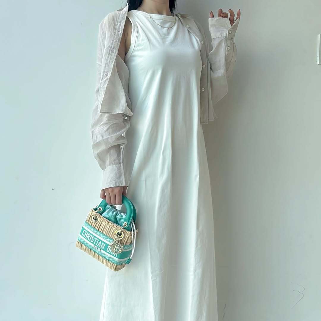 ディオールのかごバッグを持つ白いワンピースの女性