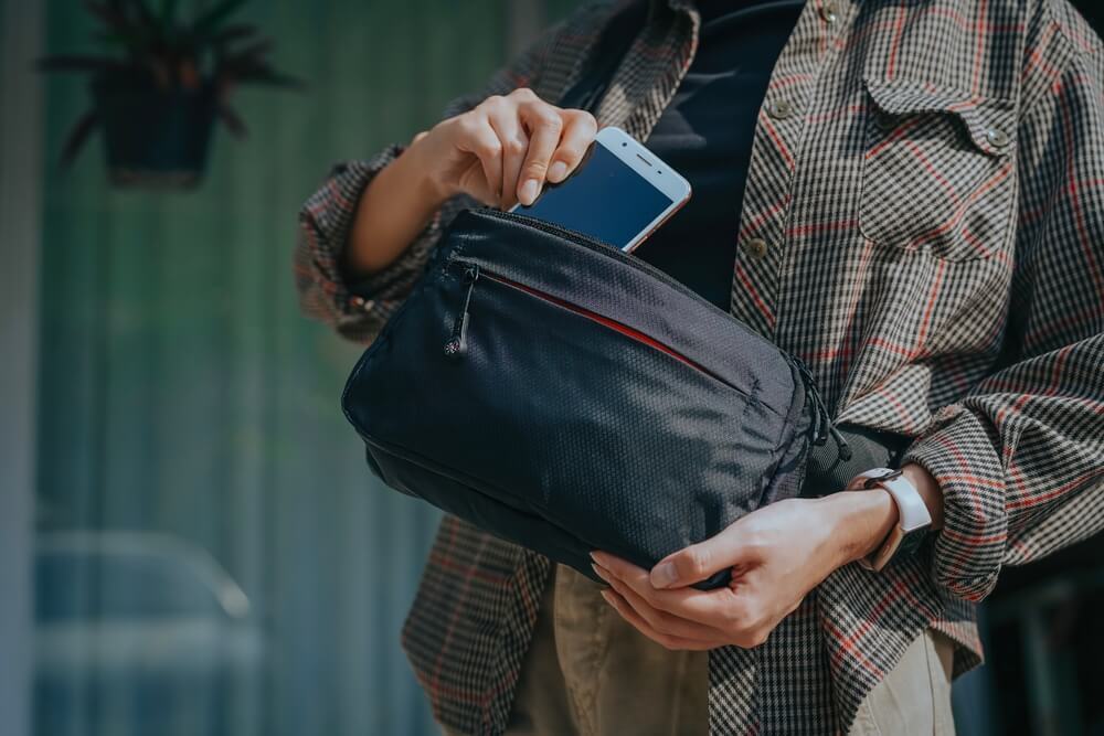 ウエストポーチにスマートフォンをしまう女性
