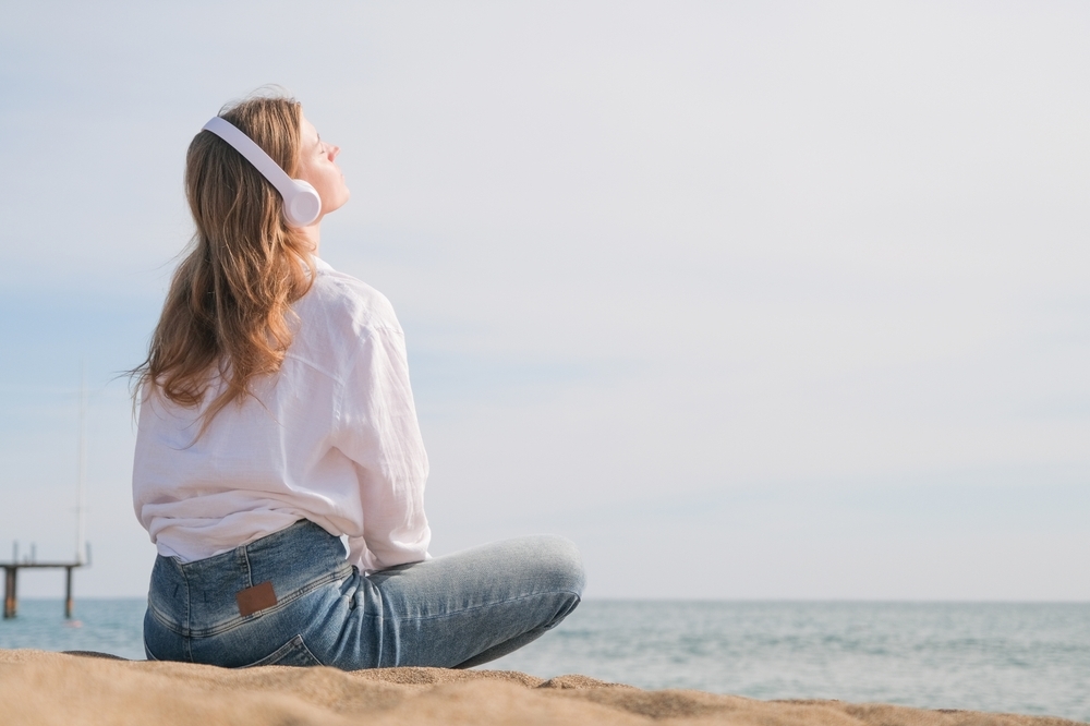 海辺で音楽を聴く女性