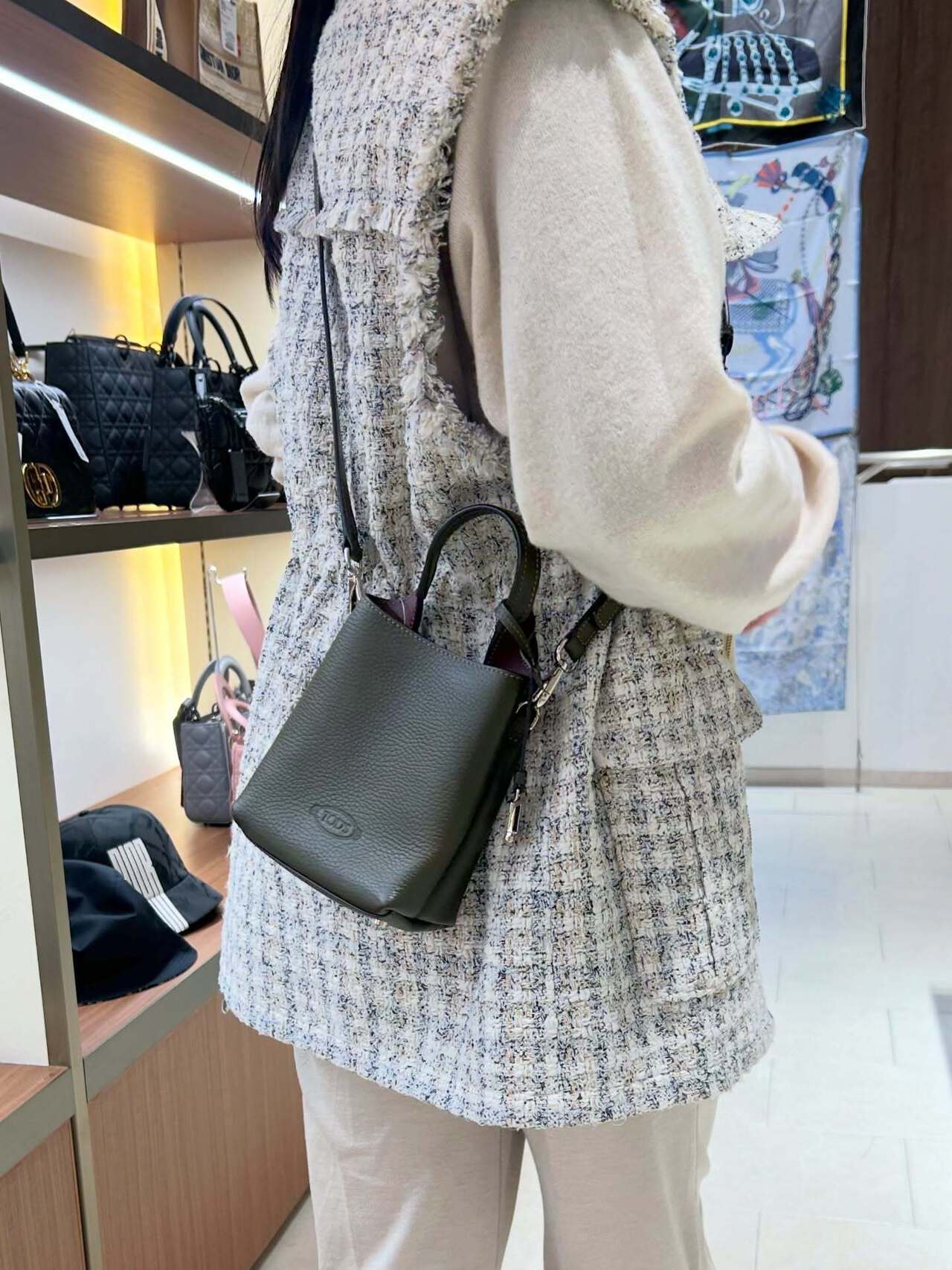 黒のミニバッグを肩にかけて買い物する女性