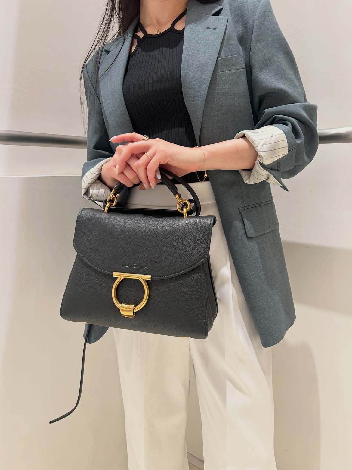 ブラックのハンドバッグを手に持つジャケットを着た女性