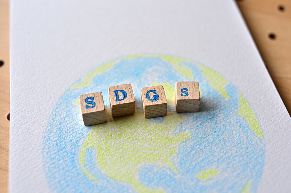 画用紙に描かれた地球の絵と、SDGsの木のブロック