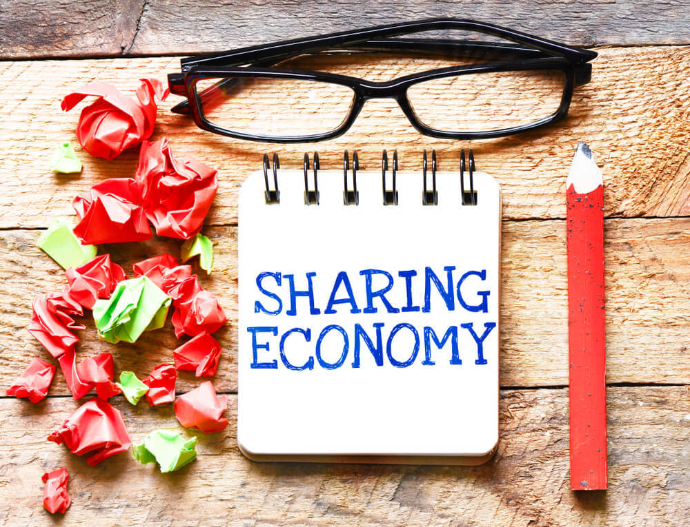 黒縁メガネと「SHARING ECONOMY」と記したメモ帳
