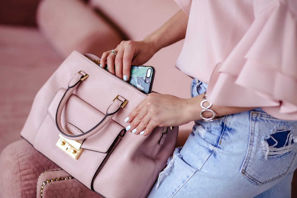 ピンクのトートバッグにスマホを入れる女性
