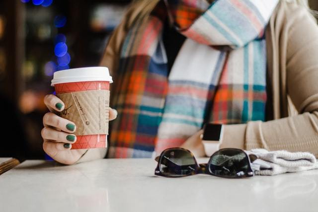 コーヒー片手にポーズを取るマフラーの女性