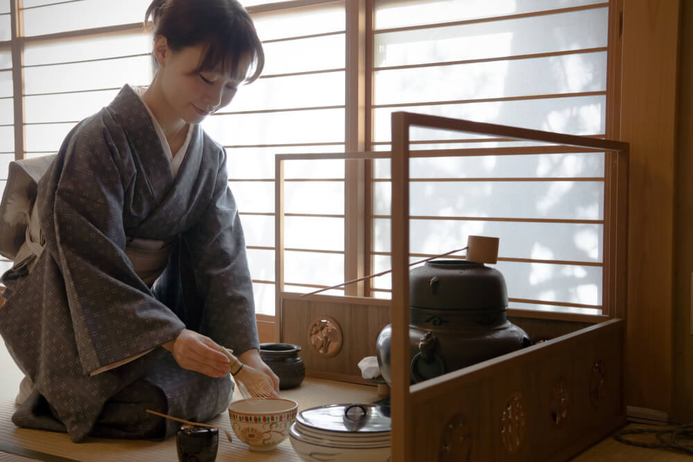 茶道の稽古をする着物女性